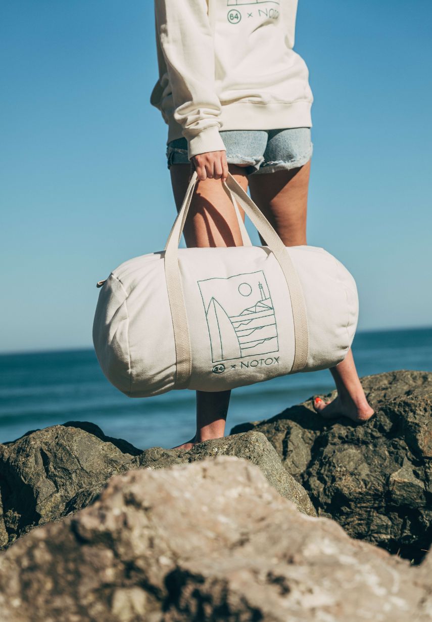 Femme sur les rochers au bord de l'océan tenant le sac polochon 64 x NOTOX